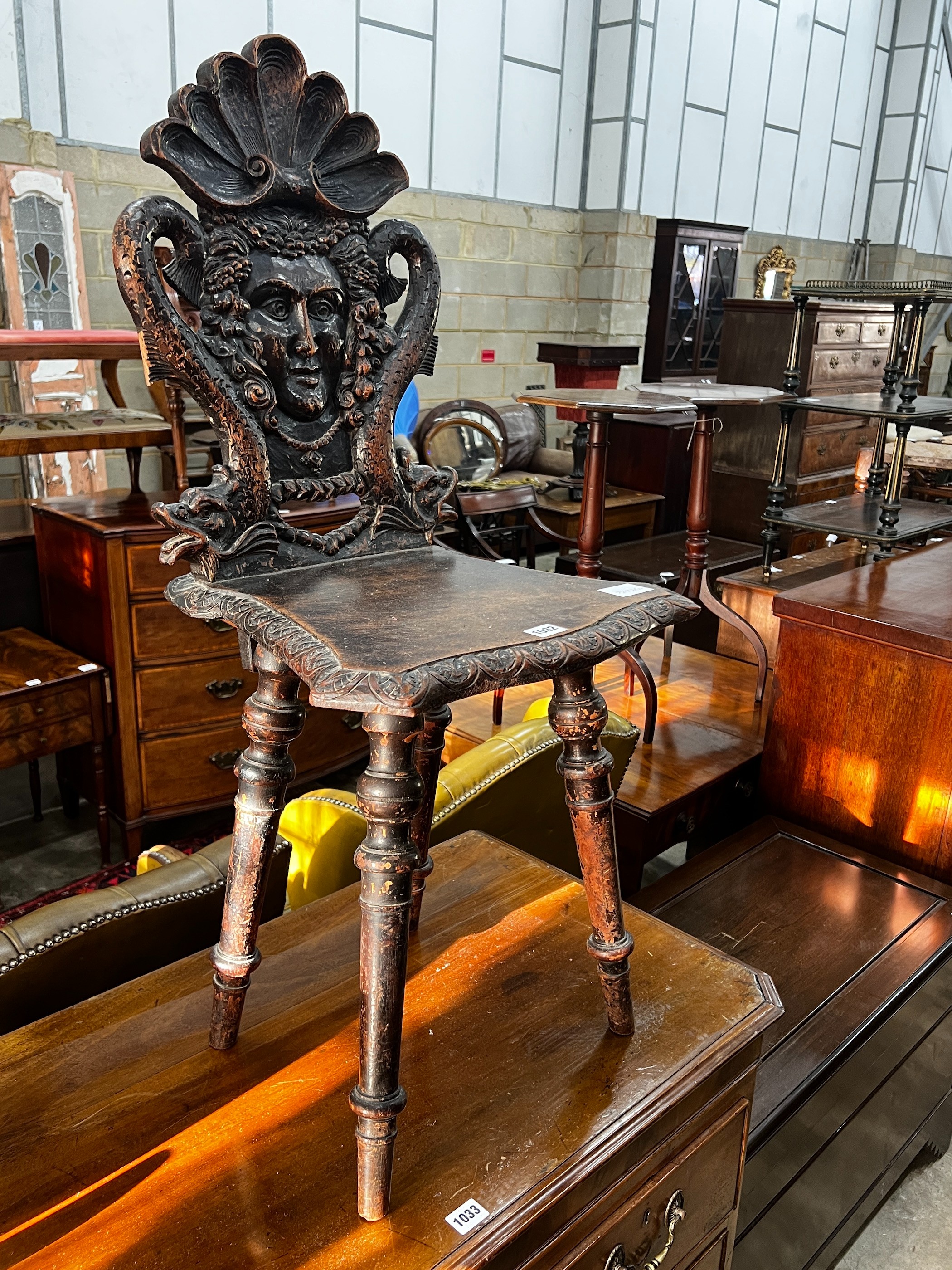 A 19th century Tyrolean oak hall chair, the back carved with a mask, a shell and serpents, height 94cm